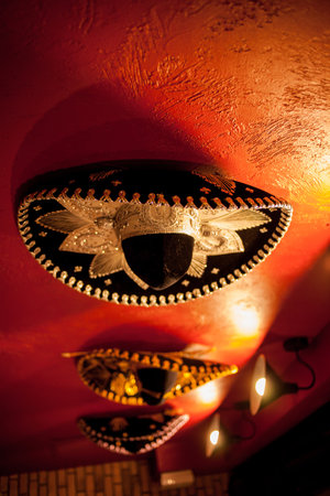 Mexican sombreros hang on the red wall, in a restaurant.の写真素材