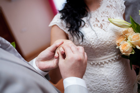 Newlyweds exchange rings, groom puts the ring on the bride's hand in marriage registry office....