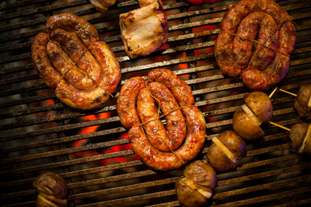 Grill sausages barbecue, fried bacon on grilled yellow and red pepper grilled, baked potato with bacon on the grill. Grilled sausages on barbecue grill. Bavarian sausages on the grillの写真素材