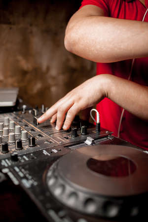 The DJ's hand on the DJ mixer. Dj on the turntables. DJ's hand on a DJ mixer close-up. Girl, Man DJ at the mixer, remote.の写真素材