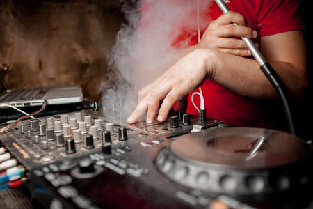 The DJ's hand on the DJ mixer. Dj on the turntables. DJ's hand on a DJ mixer close-up. Girl, Man DJ at the mixer, remote.の写真素材