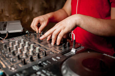 The DJ's hand on the DJ mixer. Dj on the turntables. DJ's hand on a DJ mixer close-up. Girl, Man DJ at the mixer, remote.の写真素材