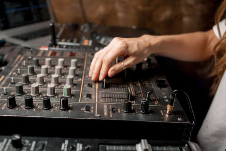 The DJ's hand on the DJ mixer. Dj on the turntables. DJ's hand on a DJ mixer close-up. Girl, Man DJ at the mixer, remote.の写真素材