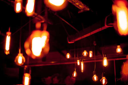 Edison lamp on a black background. Incandescent lightbulb with a dark background with bokeh. Tungsten lamps it's make feeling to warm tone. Retro Edison light bulb with an unusual spiral, with bokehの写真素材