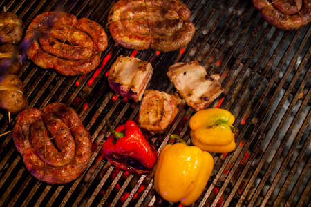 Grill sausages barbecue, fried bacon on grilled yellow and red pepper grilled, baked potato with bacon on the grill. Grilled sausages on barbecue grill. Bavarian sausages on the grillの写真素材