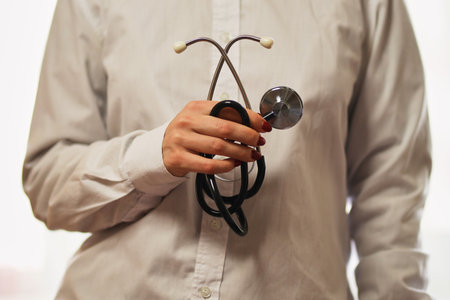 doctor with a stethoscope on hospital background. A doctor in a white coat with a stethoscope.  treatment. A doctor in a white coat holds a stethoscope in his hands. Healthcare concept.の写真素材