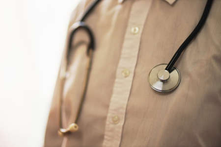 doctor with a stethoscope on hospital background. A doctor in a white coat with a stethoscope. treatment. A doctor in a white coat holds a stethoscope in his hands. Healthcare concept.の写真素材