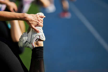 girl athlete stretches before training, girl athlete holds sneakers. The athlete prepares for running outdoors. The runner prepares to run. Sport active lifestyle concept. Close-upの写真素材