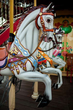 Retro carousel white, black horse. Old wooden horse carousel. Carousel Horses on vintage, retro carnival cheerful walk. CloseUp of colorful carousel with horses.の写真素材