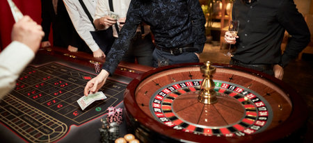 People play poker roulette at the table. Friends playing in the casino. A group of young people at a roulette table with a tape measure. Table for gambling in a luxury casino. Gambling Casino Rouletteの写真素材