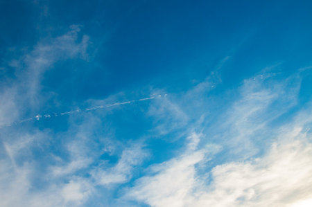 Single Interrupted chemtrail on azure sky with white clouds. Airplane trail. Curly trail. Chemtrail conspiracy theory.の写真素材
