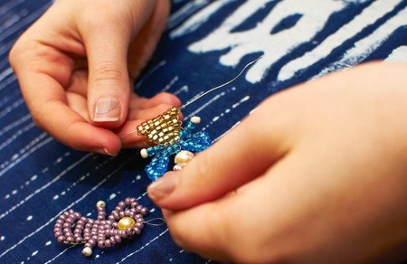 Making bobbin lace in traditional way. Detail on hands holding wooden bobbins with wound thread. Pillow lace.の写真素材