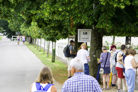 Lipica, Slovenia July 21st 2018. English tourists waiting by a sign of English language for a tour guide in Lipizzan stud farm. Tour Guide concept.のeditorial素材