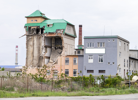 View on a partially collapsed brick industrial building with green metal roof and light sky above. Industrial silo building. White blank isolated billboardの写真素材