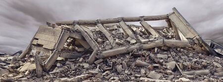 Collapsed concrete industrial building with dramatic sky and another concrete building in background. Disaster scene full of debris, dust and damaged houseの写真素材