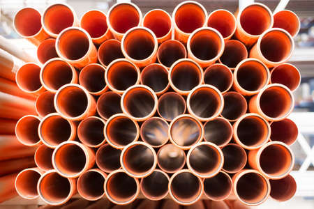Background of orange plastic sewage pipes used at the building site. Texture and pattern of plastic drainage pipe. Light through tubes.の写真素材