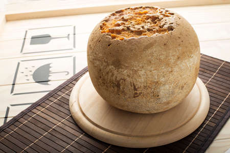 Whole Mimolette cheese loaf on a wooden plate.の写真素材