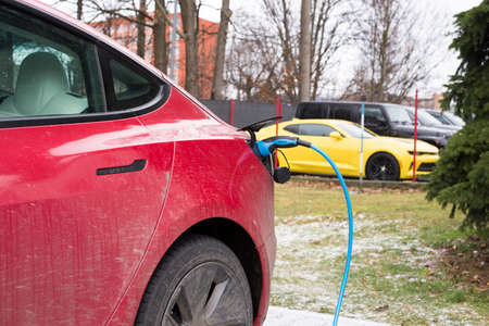 Roznov Czech Republic November 20th 2022 - Tesla model S car being charged with a yellow mussle car in backgroundのeditorial素材