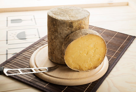 Cheddar PDO cheese cut and served on a wooden plateの写真素材