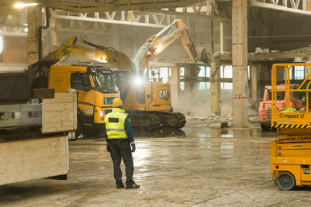 Roznov Czech Rep 4th January 2022 Worker watching heavy machinary and excavator doing construction work inside of an industrial buildingのeditorial素材