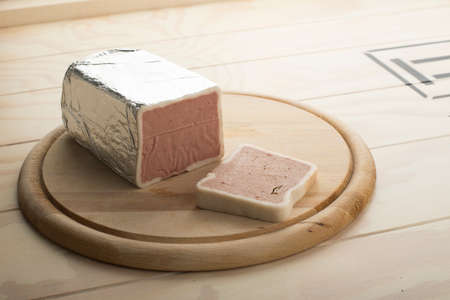 Liver-Cheese in aluminium film served on a wooden plateの写真素材