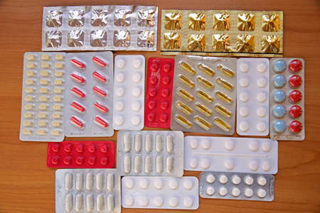 A pile of pills in blister packs. Blister packs full of multi-colored pills. Close-up on a light background. Full colored pills package. Pharmaceutical blister pack. Pack of pills with tablets.の写真素材