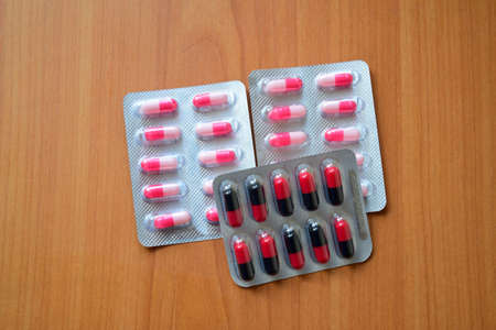 A pile of pills in blister packs. Blister packs full of multi-colored pills. Close up on wooden background. Full colored pills package. Pharmaceutical blister pack. Pack of pills with tablets.の写真素材