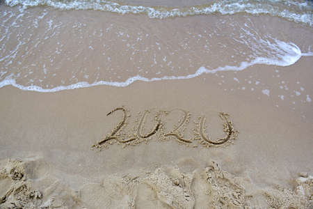 2020 text painted on the sand. Water washed away the text on the beach. The 2021 year is comingの写真素材