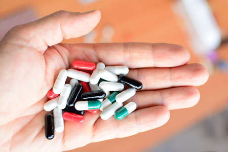 Handful of capsules of various colors lie in palm of your hand. Close-up, top view, center compositionの写真素材