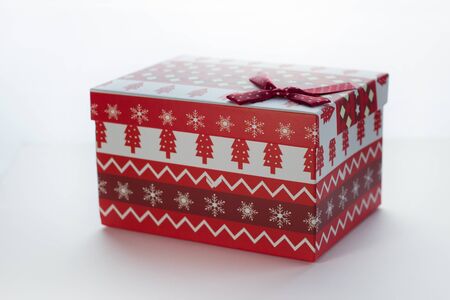 Christmas box with red gifts on white isolated background with the image of Christmas trees close-up angled. There is a bow in the cornerの写真素材