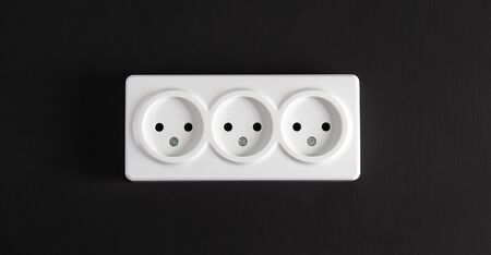 Light socket with three connectors on a black wall in a horizontal position.の写真素材