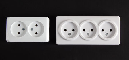 Two bright rectangular sockets lying side by side in a horizontal position on a black background.