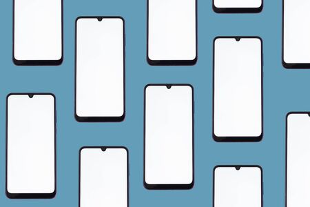 Smartphones with a blank screen in a horizontal position on a blue background.の写真素材