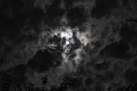 A shadow from the moon covers part of the sun against the backdrop of dramatically gray clouds and...
