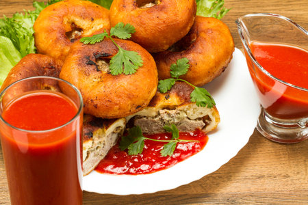 Fried patty on a plate with tomato juice and ketchup on salad