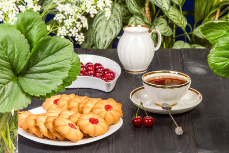 Tea fresh biscuits with cherries on the table in the morning on natureの写真素材
