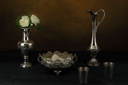 A vintage set of a jug with a cup of chocolate, a vase and a rose on the tableの写真素材