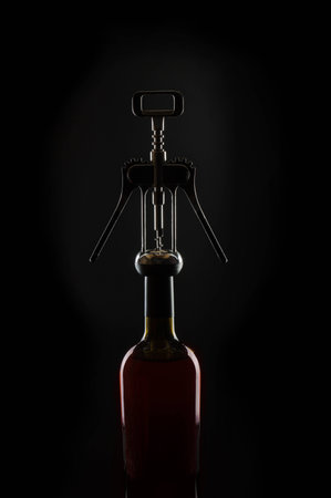 red wine on a black background in a bottle and a corkscrewの写真素材
