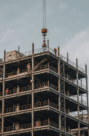 Construction site with cranes and workers on scaffolding at building siteの素材