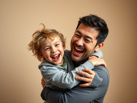 Portrait of happy father and son laughing and hugging on beige backgroundの素材