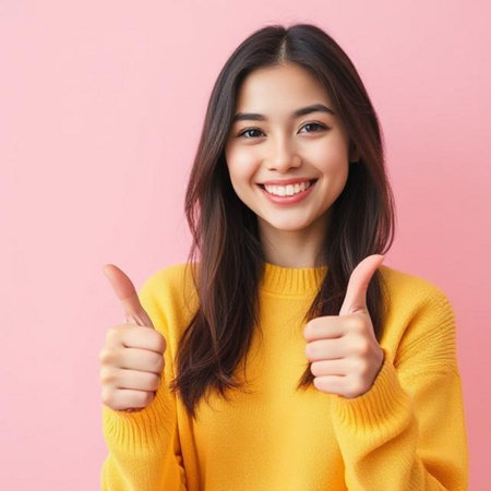 Portrait of a beautiful young Asian woman showing thumbs up over pink backgroundの素材