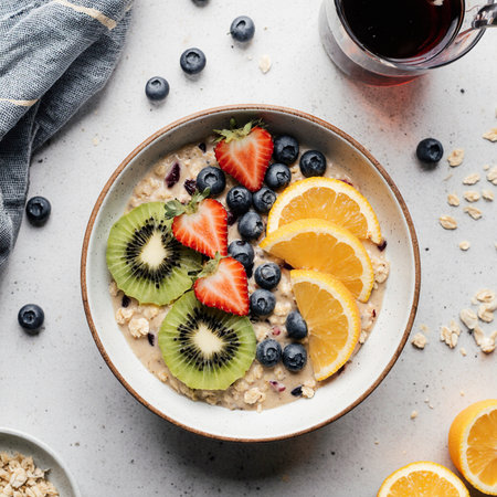 Oatmeal porridge with fresh berries, orange and kiwi in a bowlの素材