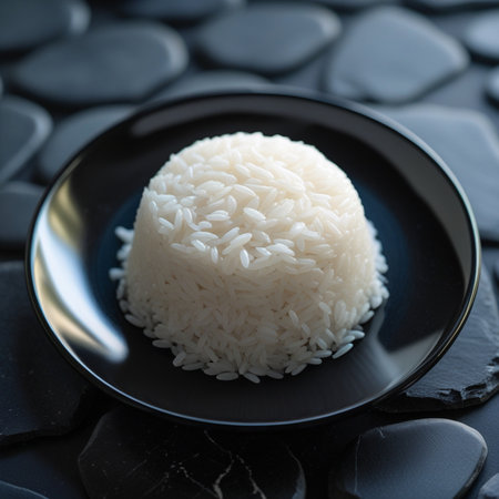 White rice in a black plate on a black stone background. Close up.の素材