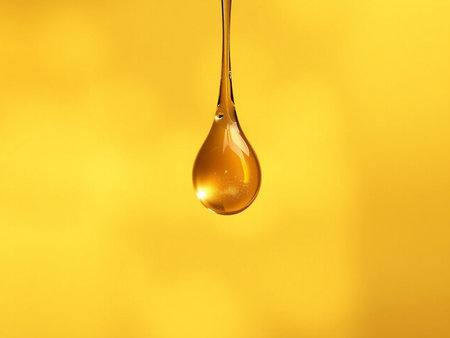 Honey dripping from a wooden honey dipper on a yellow backgroundの素材