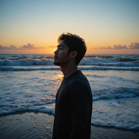 Portrait of a young man standing on the beach at sunset.の素材