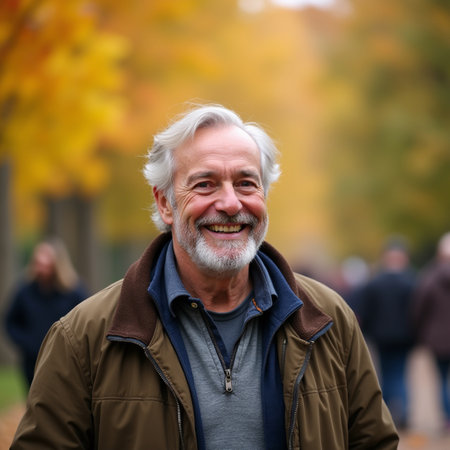 Portrait of a senior man with gray beard and mustache standing in autumn parkの素材