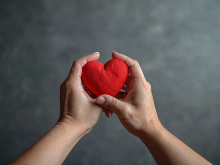 Female hands holding red heart on gray background, closeup. Space for textの素材