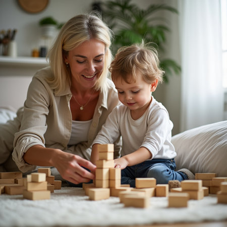 Cute little boy and his beautiful mother playing with wooden blocks at homeの素材