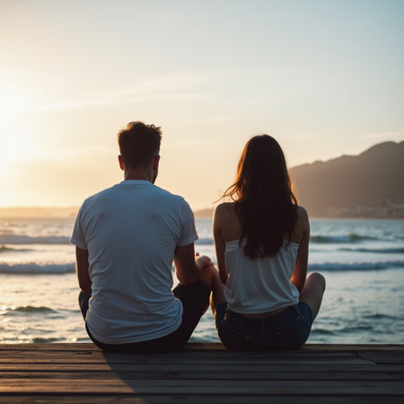 Young couple sitting on the pier and watching the sunset over the seaの素材