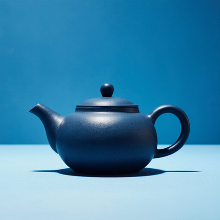 Black teapot on blue background. Studio shot. Toned.の素材
